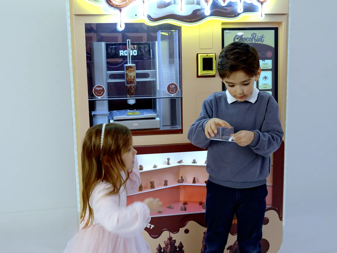 Kinder, die die Sweet Robo ChocoPrint Schokoladendruckmaschine benutzen